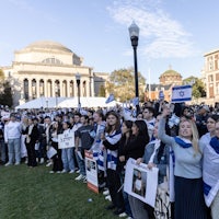 a group of people holding israeli flags in front of a building